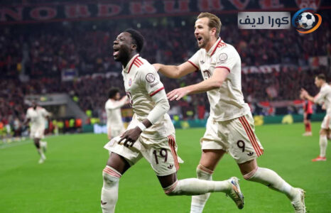 مشجعون يشاهدون مباراة في الدوري الألماني على شاشة كبيرة، مع شعار البوندسليغا في الخلفية.